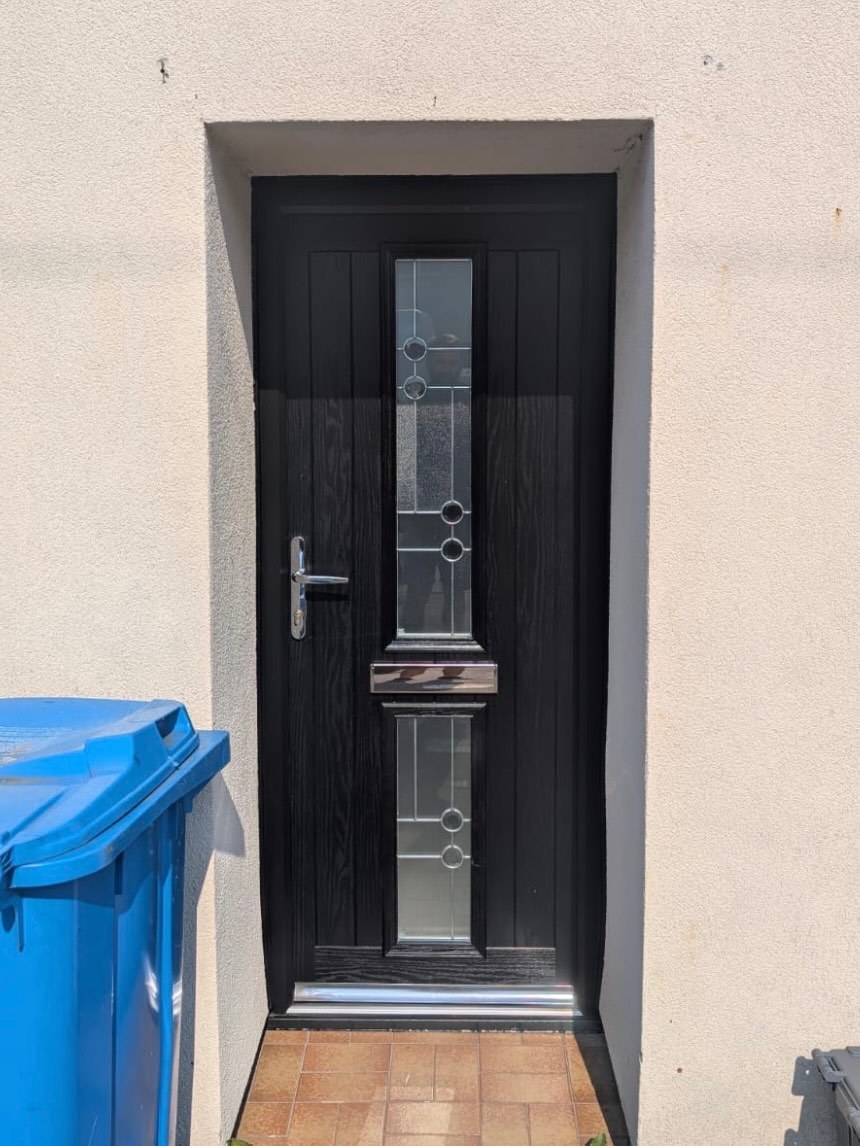 A black composite front door with three small glazed panels