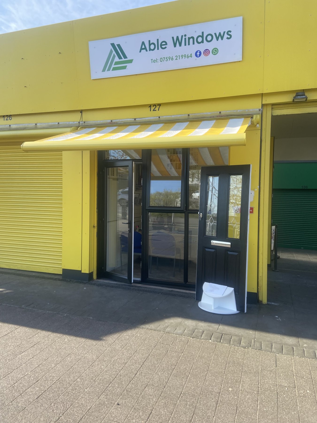 The Able Windows unit at Kirkby Market, with the sign above the door and a sample door outside